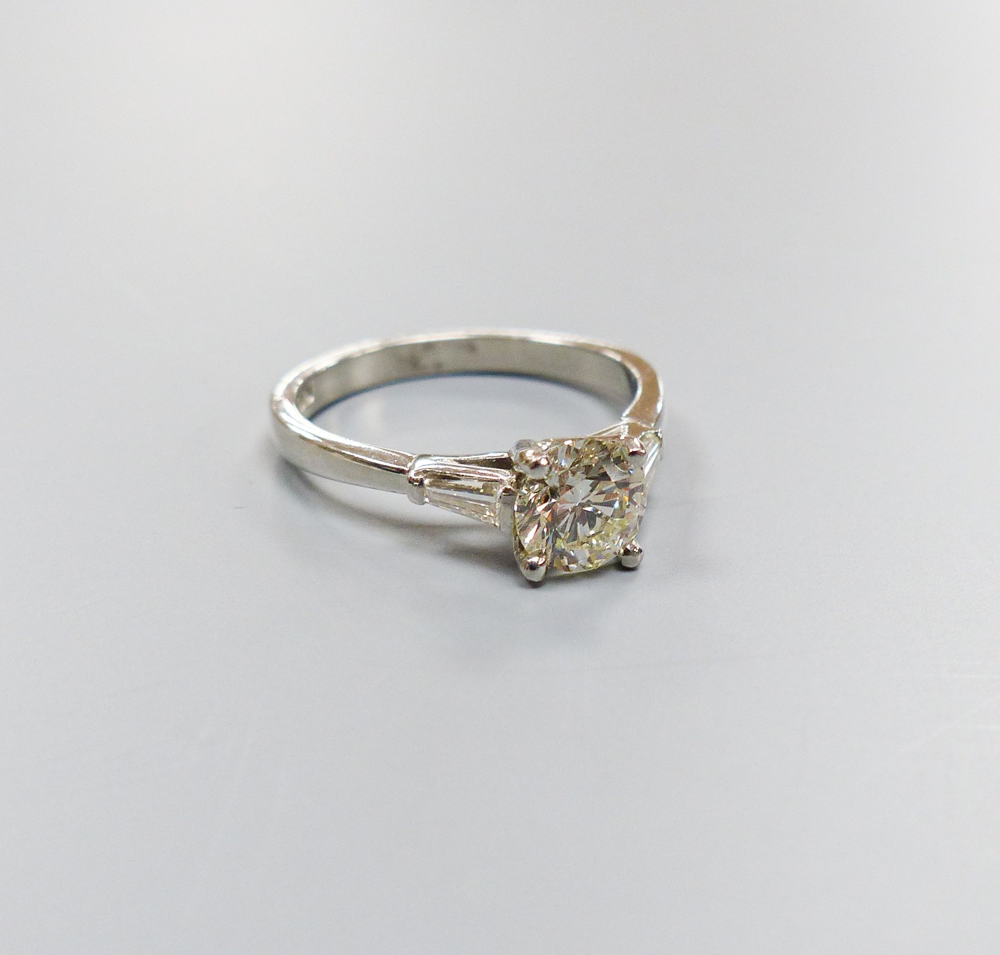 A modern platinum and single stone diamond ring, with trapeze cut diamond set shoulders, size N, gross weight 4.8 grams